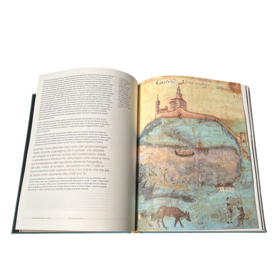 Foto del volume Archeologia Urbana a Udine. Il libro è aperto alla pagina in cui viene riportato il celebre acquerello di E. Palladio, ora conservato alla Biblioteca Civica V. Joppi di Udine. In esso vengono raffigurati il Castello di Udine, cinto di mura, il suo colle e il laghetto che sorgeva in corrispondenza dell'attuale piazza Primo Maggio; nel disegno sono apprezzabili anche un moletto e un'imbarcazione, e in primo piano, un animale selvatico e due persone intente a conversare.