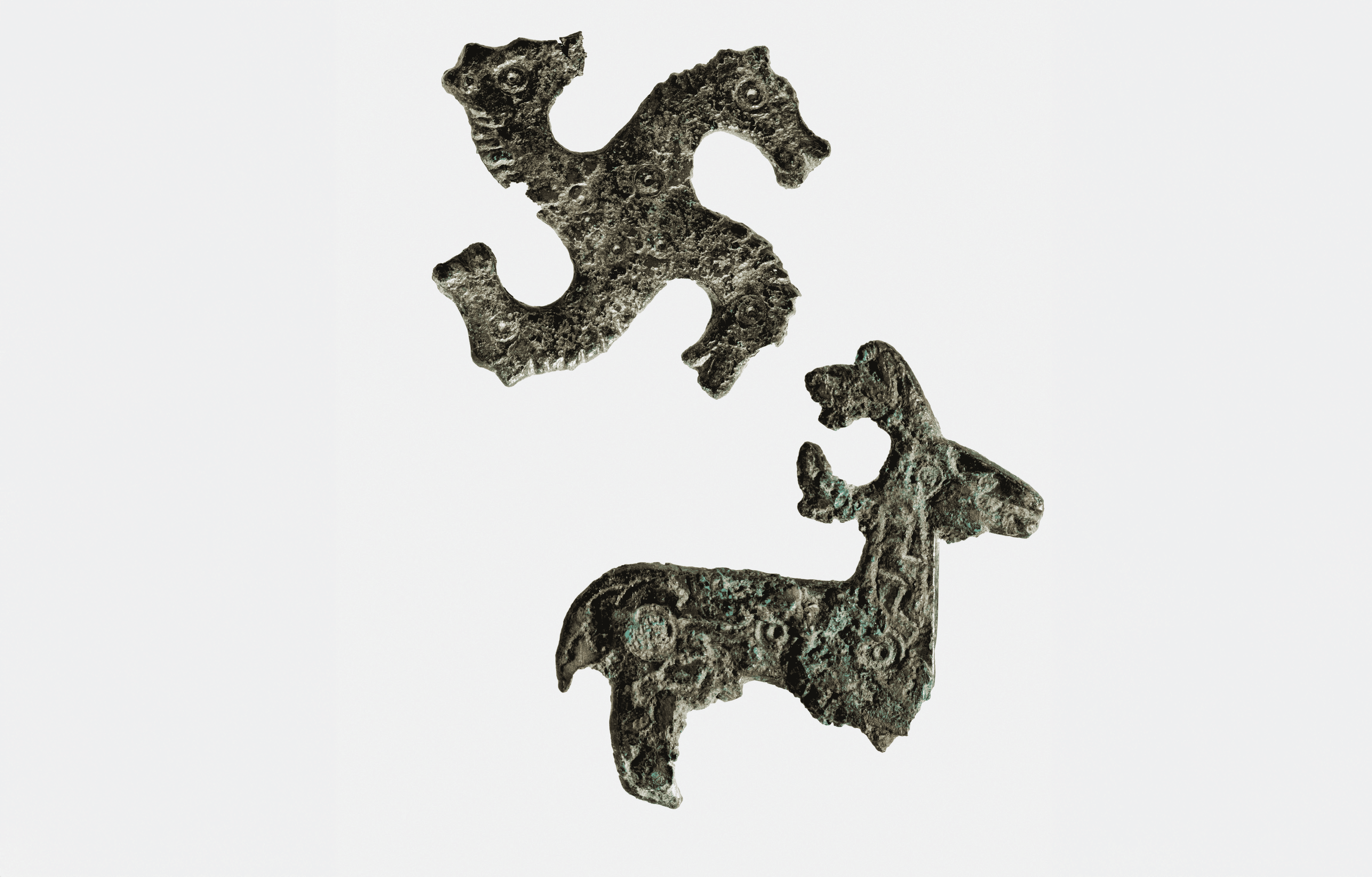 Fibula a croce con quattro teste di cavallo e fibula a forma di cervo, databili tra VI e VII sec. d.C., rivenute durante gli scavi presso il versante orientale del Castello nel 1986-1987 (Fototeca dei Civici Musei di Udine, foto L. Laureati)